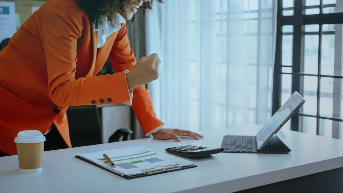 Professional reviewing work at a laptop in an office setting.